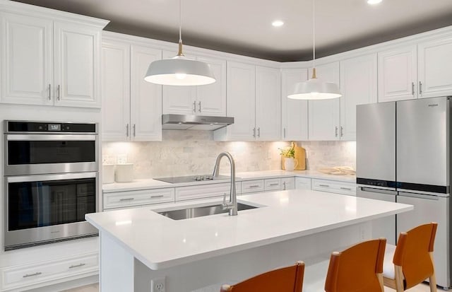 kitchen featuring pendant lighting, stainless steel appliances, a breakfast bar, and white cabinets