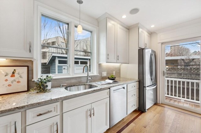 kitchen with white cabinets, dishwasher, freestanding refrigerator, light wood-type flooring, and a sink