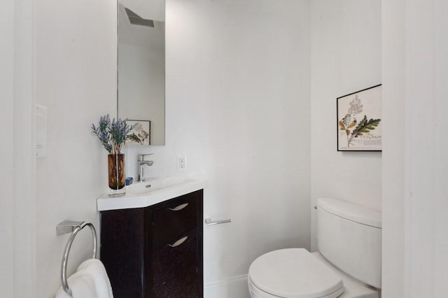 bathroom featuring baseboards, vanity, and toilet