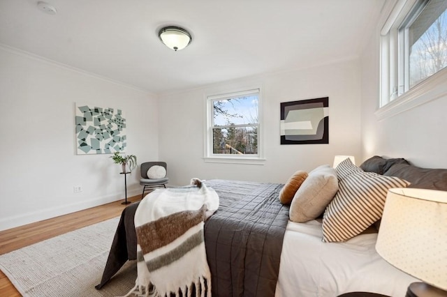 bedroom featuring crown molding, baseboards, and wood finished floors