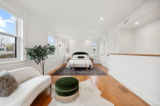 bedroom featuring light wood finished floors, multiple windows, and crown molding