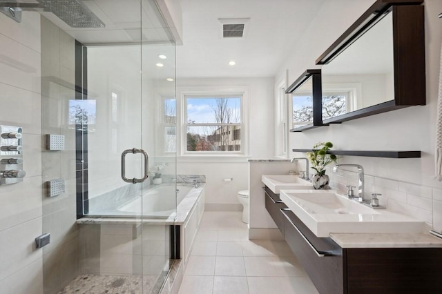 full bathroom with visible vents, toilet, a sink, a shower stall, and a bath