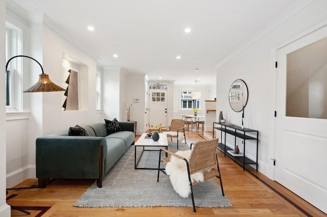 living area with baseboards, ornamental molding, recessed lighting, and light wood-style floors