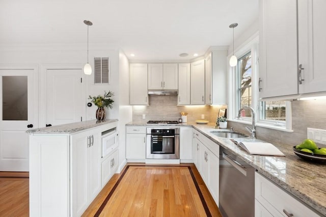 kitchen with under cabinet range hood, stainless steel appliances, a peninsula, a sink, and visible vents