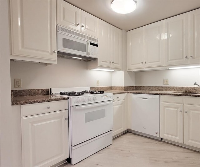 kitchen with a sink, white cabinets, white appliances, and light wood-style flooring