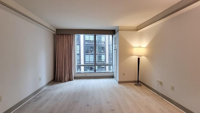 empty room featuring baseboards and light wood finished floors