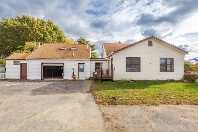 view of front of property with a front lawn, roof with shingles, a chimney, a garage, and driveway