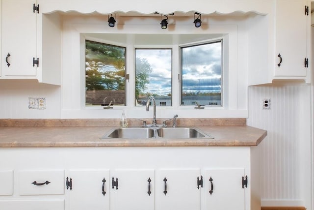 kitchen featuring white cabinets, light countertops, and a sink