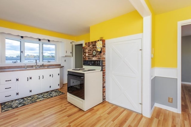 kitchen featuring a sink, light wood-type flooring, white cabinets, and white range with electric stovetop