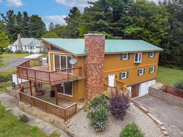 rear view of property with a wooden deck and a garage