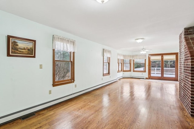 spare room with ceiling fan, plenty of natural light, light hardwood / wood-style floors, and a baseboard heating unit