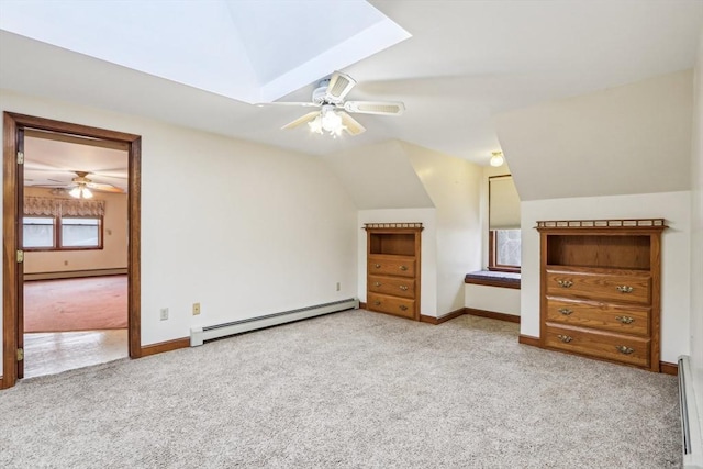 unfurnished bedroom featuring vaulted ceiling with skylight, baseboard heating, and light carpet