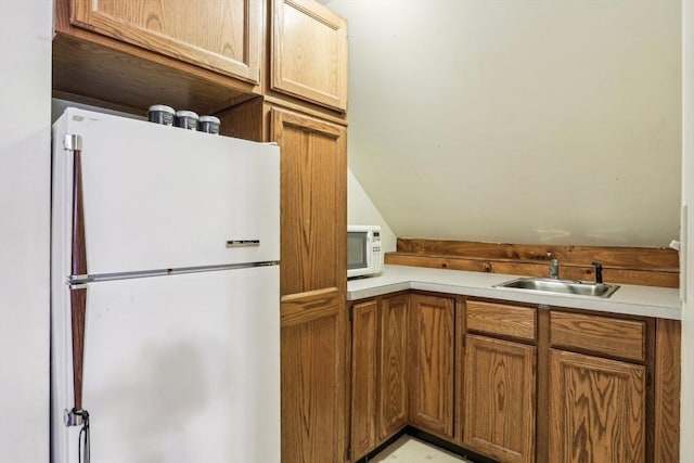 kitchen with vaulted ceiling, sink, and white appliances