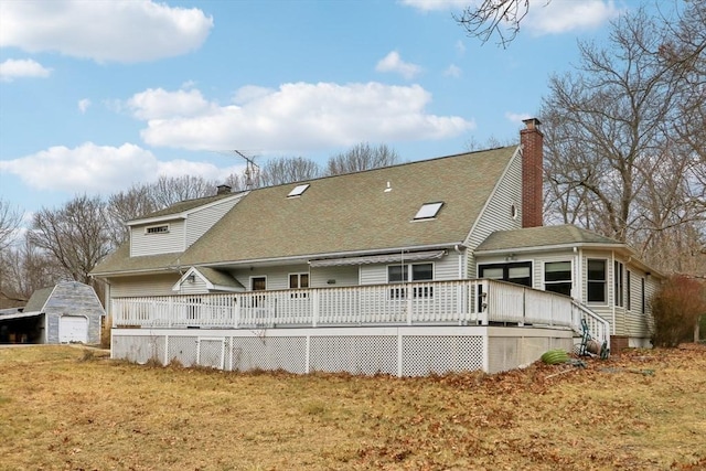 back of property with a lawn, an outdoor structure, a garage, and a deck