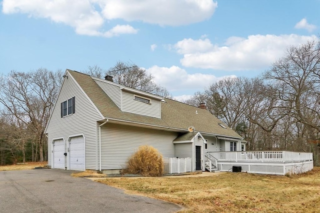 view of front of property featuring a front yard, a deck, and a garage