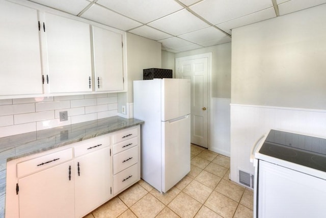 kitchen with light tile patterned flooring, white cabinetry, a paneled ceiling, white refrigerator, and range with electric cooktop