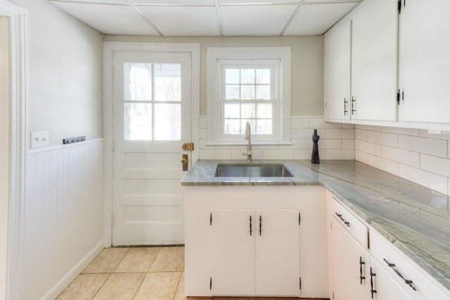 kitchen with sink, light tile patterned floors, a paneled ceiling, tasteful backsplash, and white cabinets