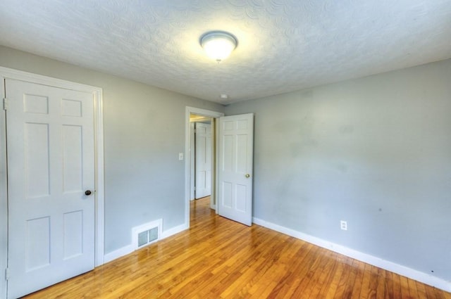 unfurnished bedroom featuring light hardwood / wood-style flooring and a textured ceiling