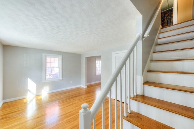 stairway with hardwood / wood-style floors and a textured ceiling