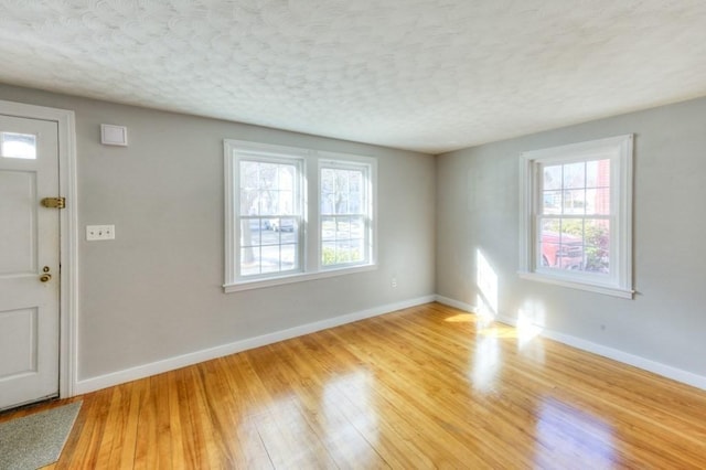 foyer entrance with a healthy amount of sunlight, a textured ceiling, and light hardwood / wood-style flooring