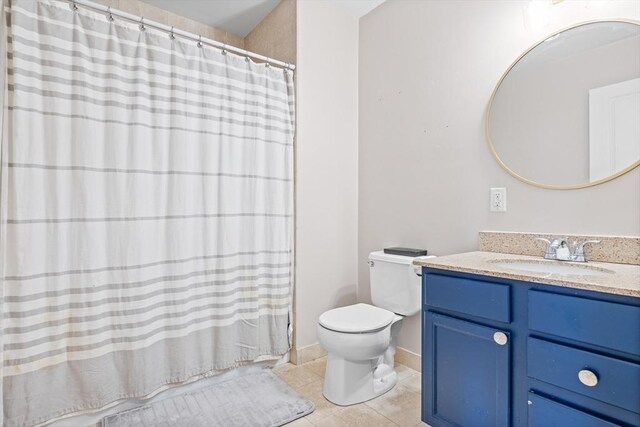 bathroom featuring tile patterned flooring, toilet, vanity, and curtained shower