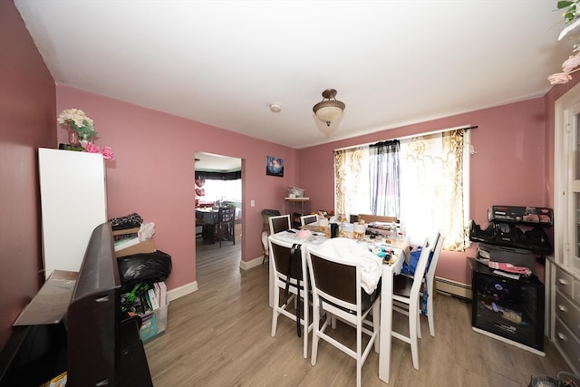 dining room with light hardwood / wood-style flooring, baseboard heating, and plenty of natural light