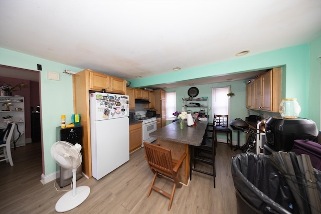 kitchen featuring light hardwood / wood-style floors, a breakfast bar area, and white appliances