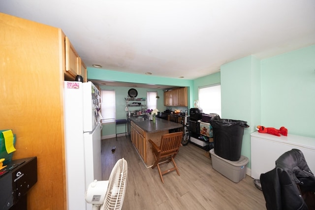 kitchen with light hardwood / wood-style flooring, a kitchen island, and white refrigerator