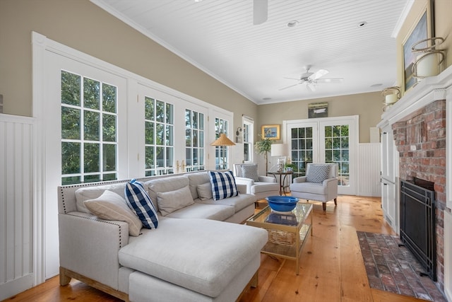 living room with ornamental molding, a brick fireplace, ceiling fan, and light hardwood / wood-style flooring