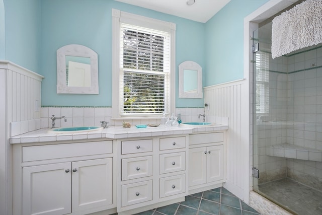 bathroom featuring tile patterned flooring, a shower with shower door, and vanity