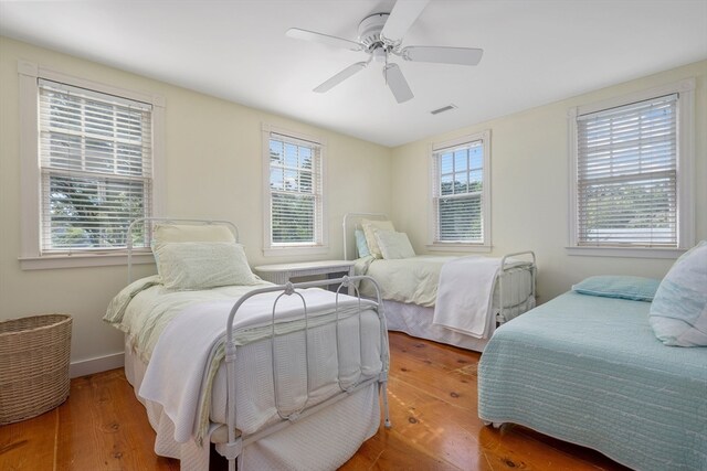 bedroom with multiple windows, ceiling fan, and hardwood / wood-style floors