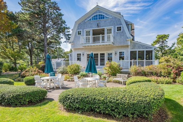 back of house featuring a balcony, a sunroom, a yard, and a patio area