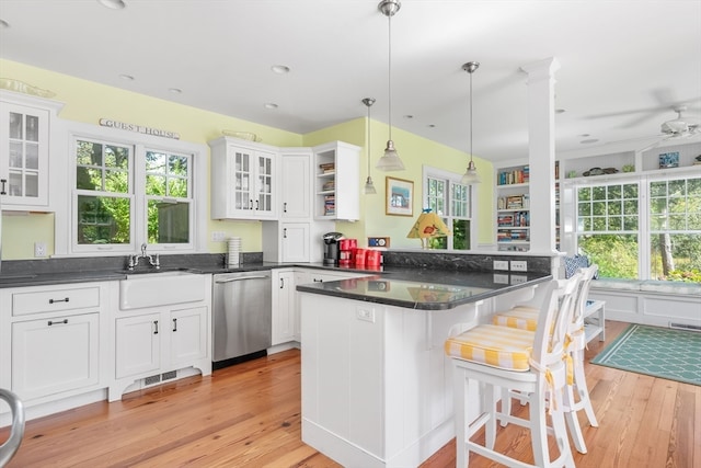 kitchen with light wood-type flooring, hanging light fixtures, white cabinetry, and stainless steel dishwasher