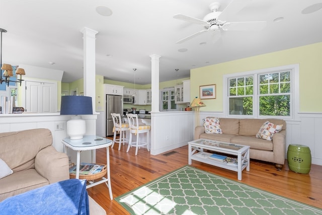 living room featuring ornate columns, hardwood / wood-style flooring, and ceiling fan