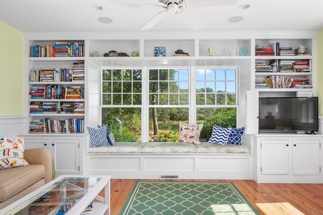 living area featuring ceiling fan, built in features, and light hardwood / wood-style flooring