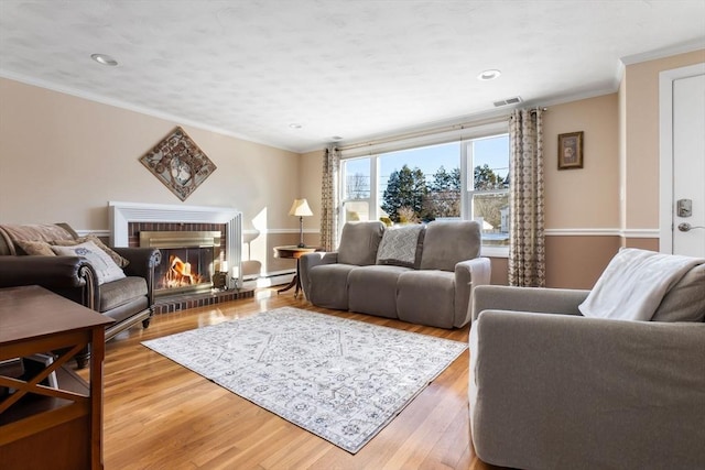 living room with crown molding, a brick fireplace, hardwood / wood-style floors, and baseboard heating