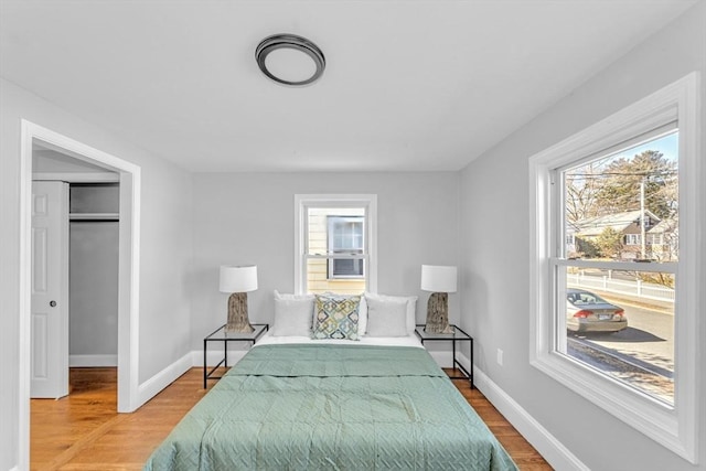 bedroom featuring baseboards, multiple windows, and wood finished floors