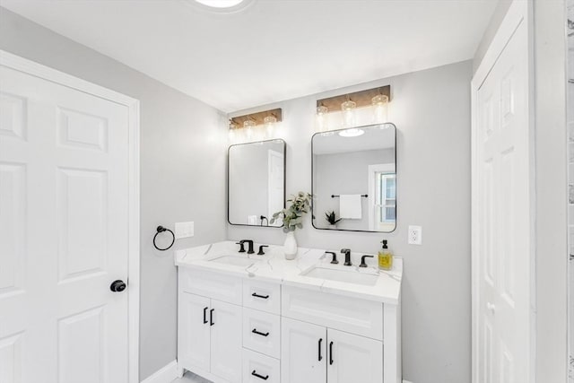 full bathroom featuring a sink, baseboards, and double vanity