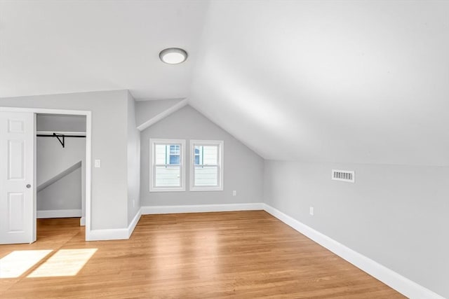 additional living space with visible vents, light wood-style flooring, lofted ceiling, and baseboards