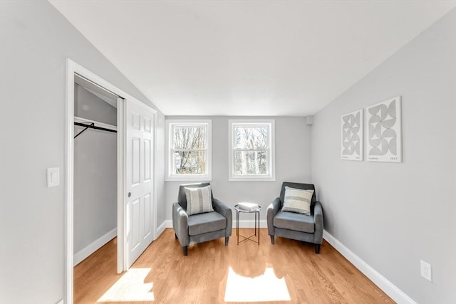 sitting room featuring baseboards, lofted ceiling, and light wood-style flooring