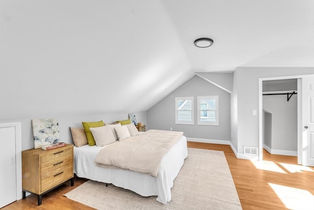 bedroom featuring vaulted ceiling, light wood-style flooring, baseboards, and visible vents