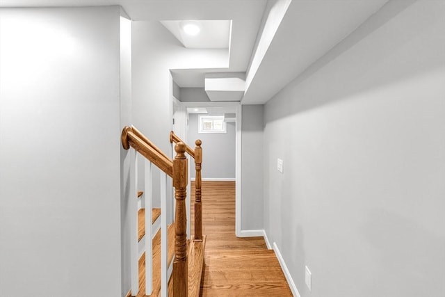 hall with baseboards, stairs, and light wood-style floors