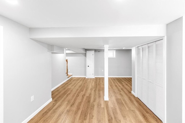 finished below grade area with light wood-style flooring, stairs, and baseboards