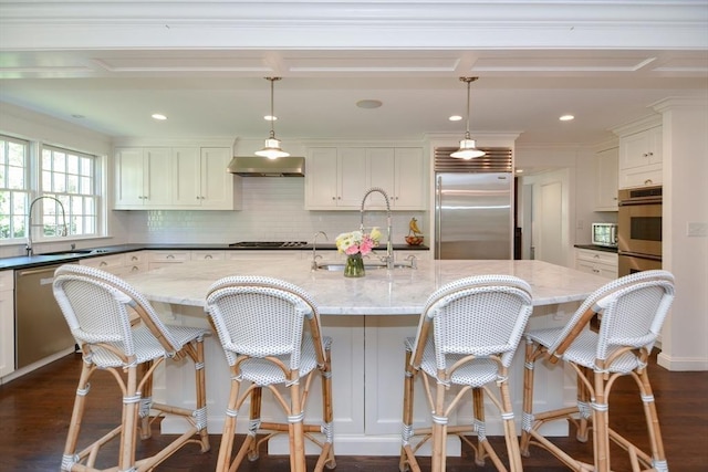 kitchen featuring dark wood-style flooring, a sink, decorative backsplash, and appliances with stainless steel finishes