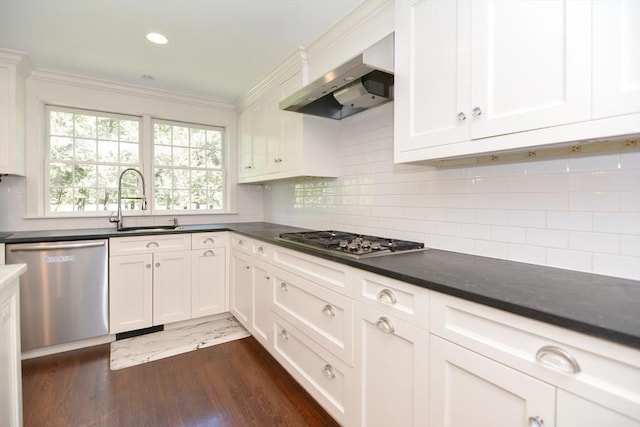 kitchen with wall chimney range hood, dark countertops, appliances with stainless steel finishes, and a sink