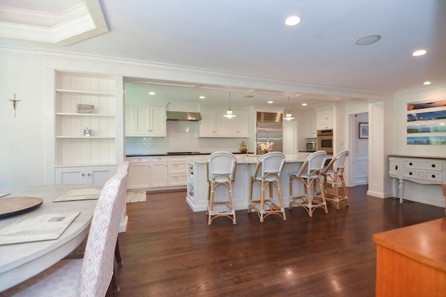 kitchen featuring ornamental molding, wall chimney exhaust hood, gas stovetop, and built in refrigerator