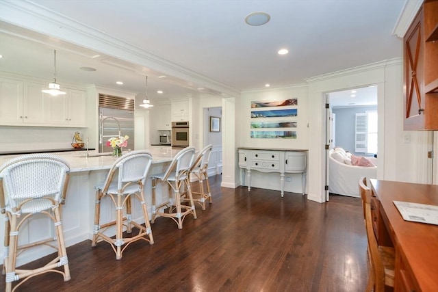 kitchen featuring a kitchen breakfast bar, dark wood-style flooring, crown molding, light stone counters, and stainless steel appliances