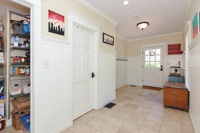 interior space featuring light tile patterned floors, a wainscoted wall, crown molding, and a decorative wall
