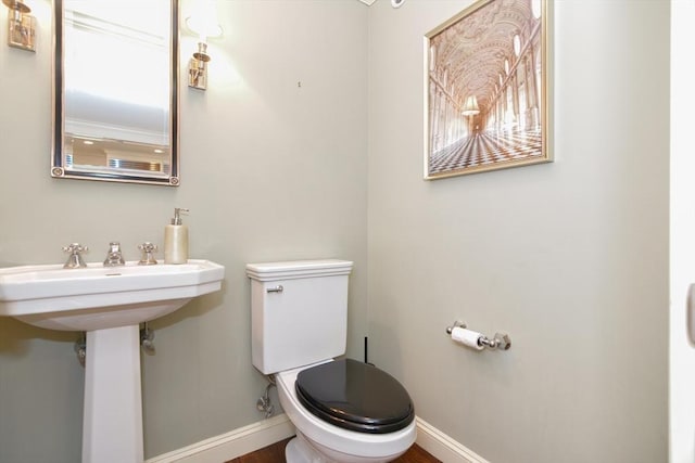 bathroom featuring baseboards, wood finished floors, and toilet