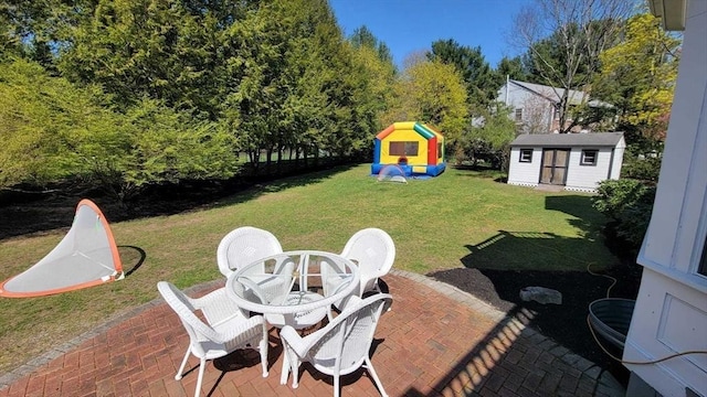 view of yard with a storage shed, an outbuilding, outdoor dining area, and a patio area